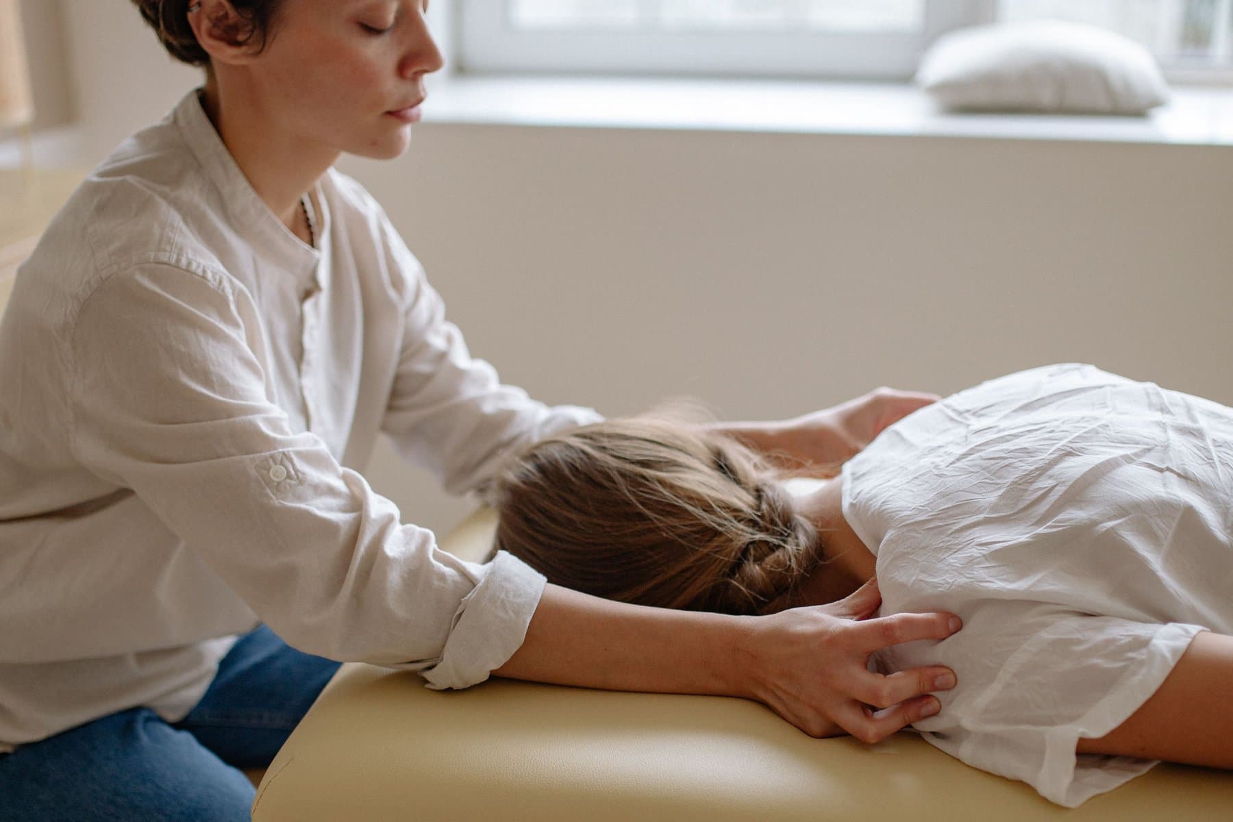 Kiputerapeutti tutkii asiakkaan niska-hartiaseutua hoitopöydällä